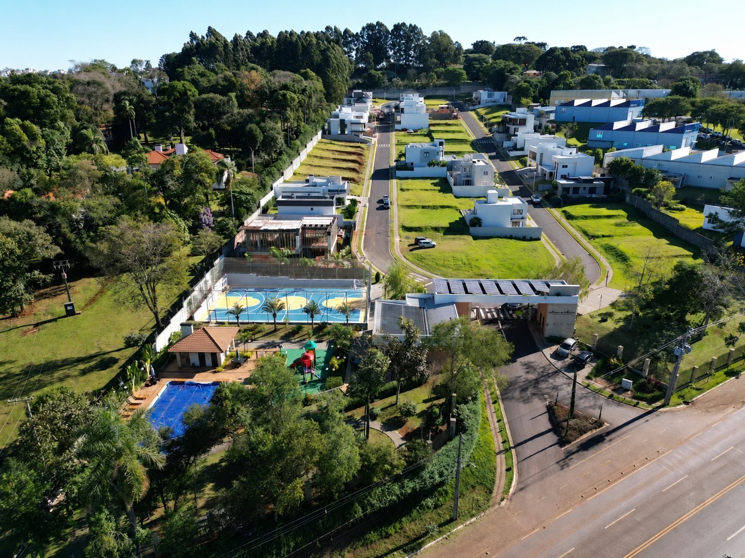 Vista aérea do Condomínio Jardins de Monet, com quadra poliesportiva, piscina e portaria